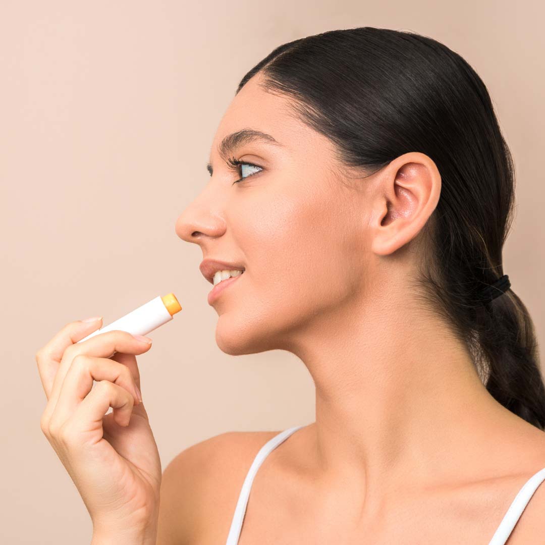 Mujer aplic&aacute;ndose b&aacute;lsamo labial